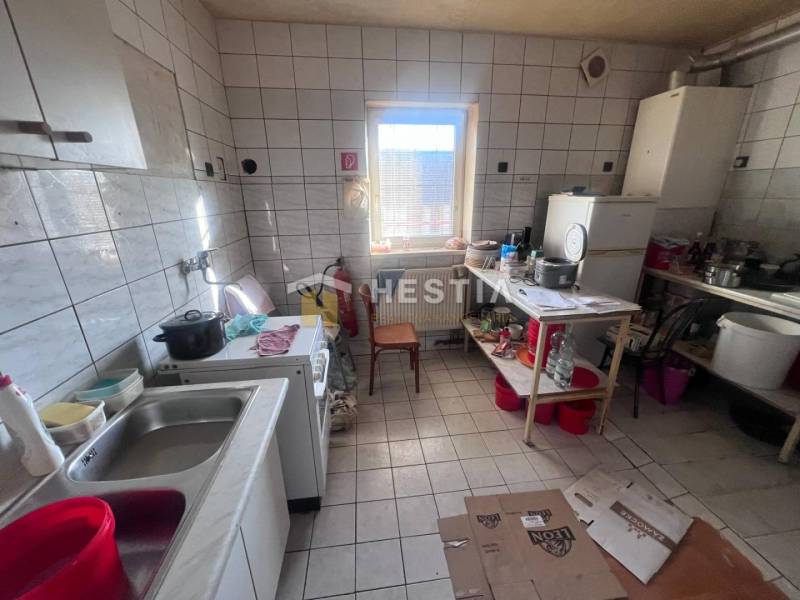 Kuchyně s podlahou z dlaždic, sporákem a nádobím na poličce, gastro prostory.