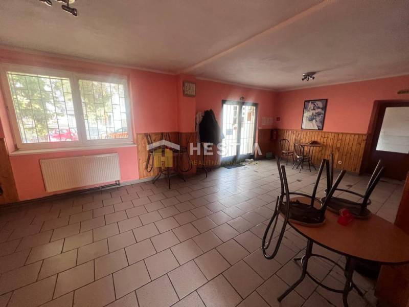 Gastro prostory s cihlovou podlahou, dřevěným dekorem na stěnách a stoly.