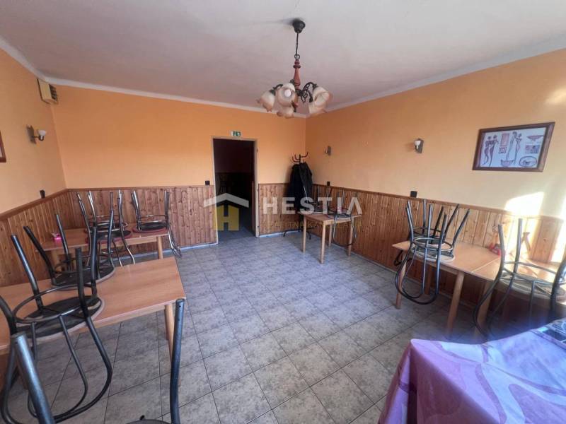 Oranžově laděné gastro prostory s kachličkovou podlahou, stoly s obrácenými židlemi.