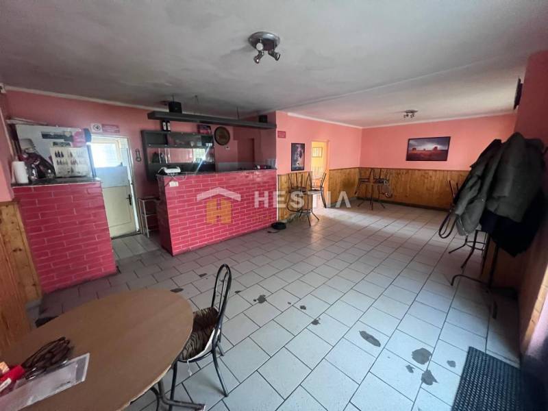 Interiér gastro prostoru s červeným cihlovým pultem a růžovými stěnami.