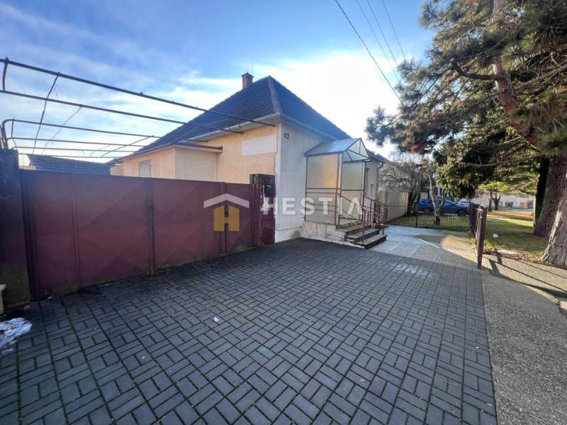 Rodinný dům se zahradou v Senici, velká vstupní brána, dlážděný dvůr, strom.