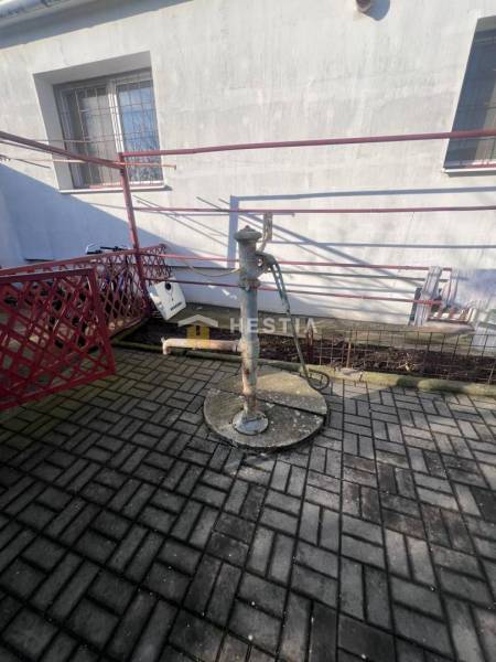 Vodní pumpa na betonové dlažbě u budovy v Gastroprostorech v Senici.