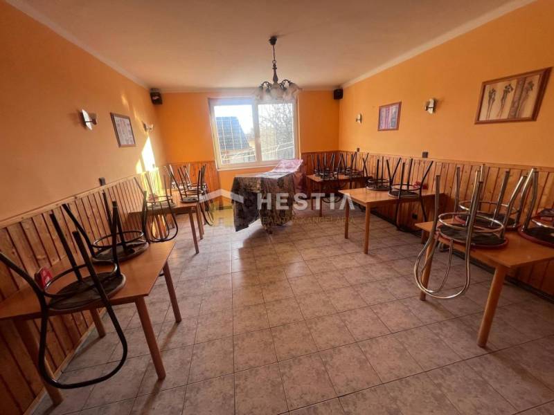 Gastro prostory s dlažbou, židle na stolech, oranžové stěny a okno do dvora.