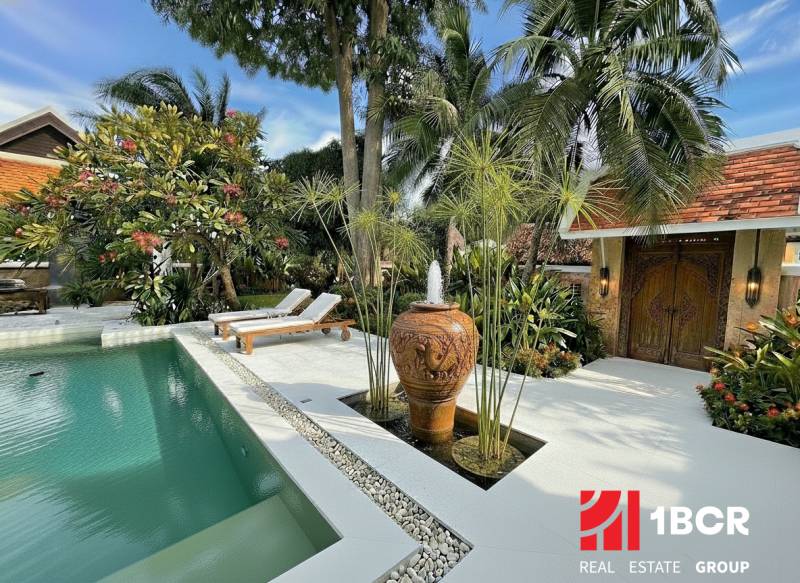 Pohled na luxusní vilu v Pattayi s bazénem a exotickou zahradou.