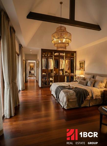 Stylová ložnice ve vile s podlahou s dřevěným dekorem a otevřenou šatnou.