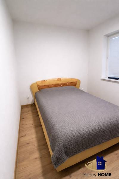 Ložnice v 2pokojovém bytě s postelí a podlahou s dřevěným dekorem.