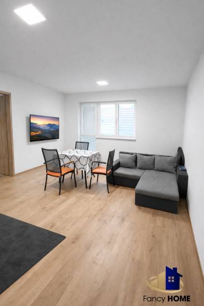 Obývací pokoj s pohovkou a stolem v 2-pokojovém bytě, podlaha s dřevěným dekorem.