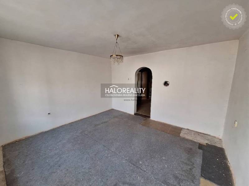 Interiér místnosti s bílými stěnami, koberec a lustr, Pozemky - bydlení.