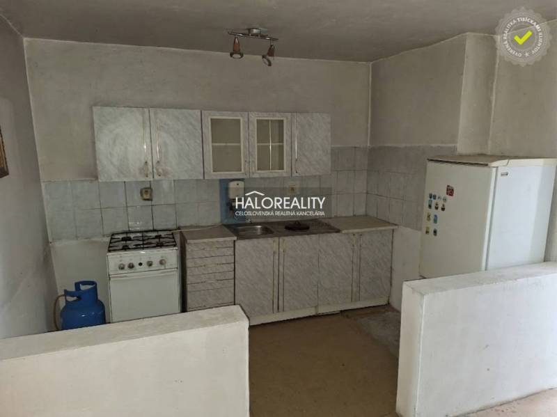 Kuchyňská linka s plynovým sporákem a lednicí v interiéru. Pozemky - bydlení.