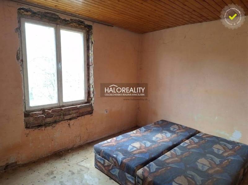 Pokoj s postelí, neopracovanými stěnami a dřevěným stropem, kategorie Pozemky - bydlení.