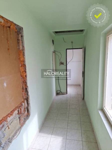 Úzký interiér se světle zelenými stěnami a podlahou s dlažbou.