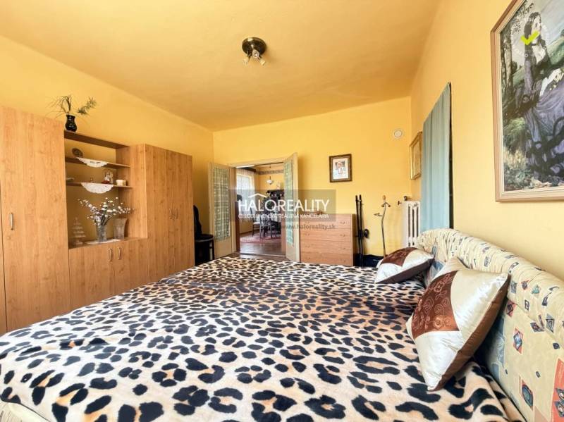 Ložnice v rodinném domě s postelí s leopardím vzorem a skříní s dekorem dřeva.