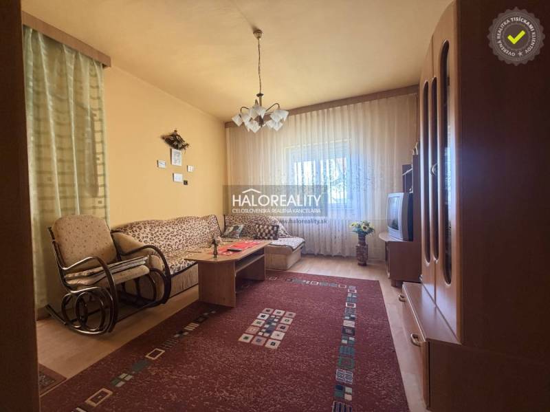 Obývací pokoj v rodinném domě s pohodlnou sedačkou a podlahou s dřevěným dekorem.