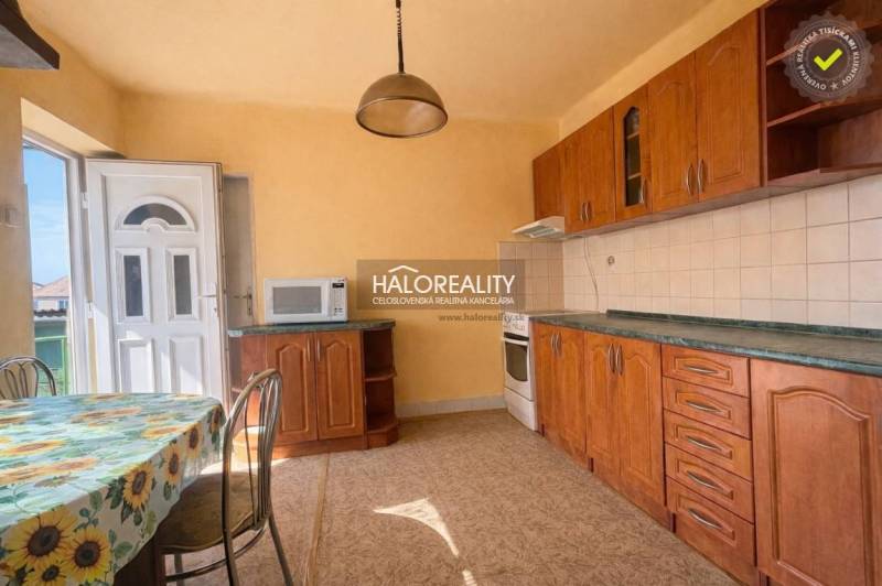 Kuchyně rodinného domu s dřevěným dekorem a slunečním stěnovým dekorem.