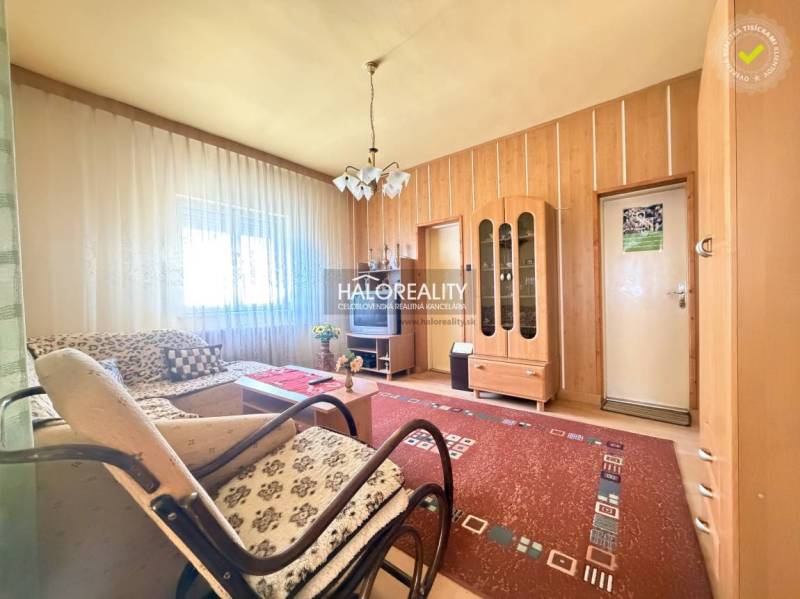 Obývací pokoj v rodinném domě se světlem z okna, dřevěný dekor stěn a nábytek.