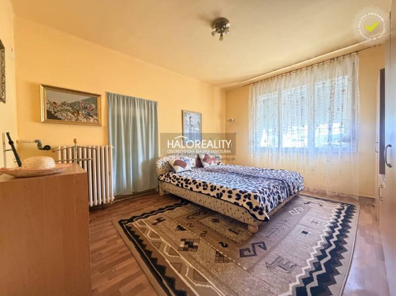 Ložnice v rodinném domě s podlahou s dřevěným dekorem, velkým oknem a koberci.