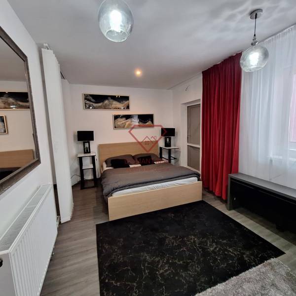 Ložnice v rodinném domě se zrcadlem, červenými závěsy a dekoracemi na stěně.