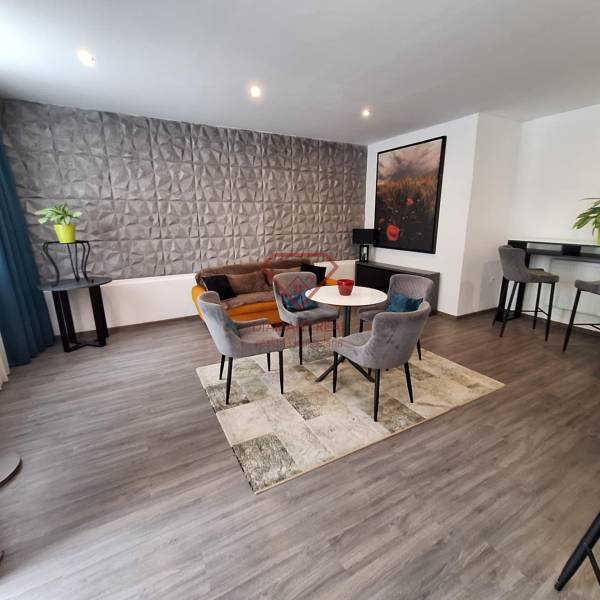 Obývací pokoj s křesly a pohovkou v rodinném domě, dekorativní stěna a barový kout.