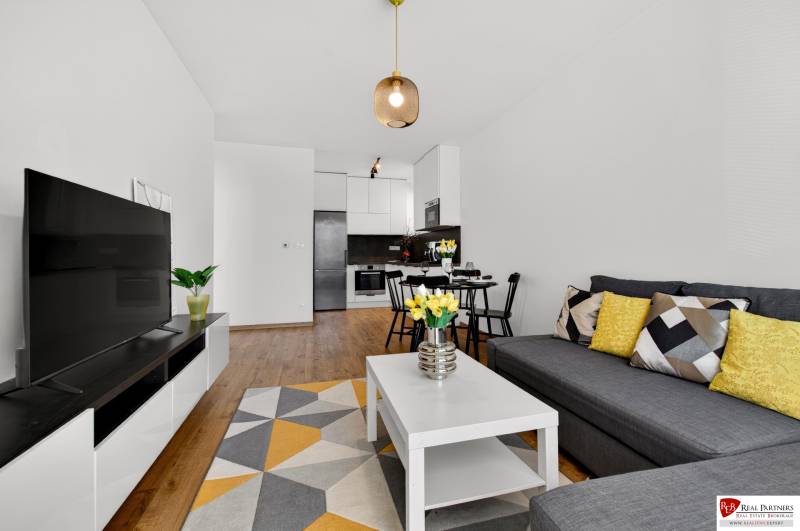 Obývací pokoj v 2-pokojovém bytě s pohovkou, stolkem a podlahou s dřevěným dekorem.