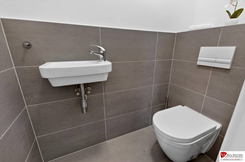 Koupelna s umyvadlem a toaleta v 2-pokojovém bytě s jednoduchými obklady.