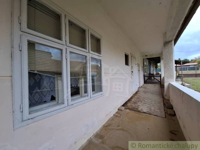 Veranda u rodinného domu v Mužle s okenními žaluziemi a zahradou v pozadí.