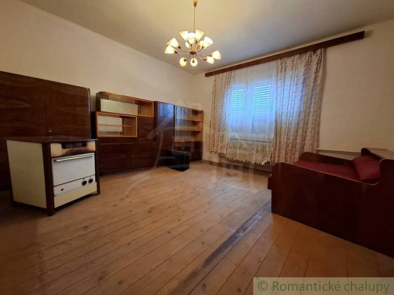 Obývací pokoj v rodinném domě s dřevěným dekorem, záclonami a pohovkou.