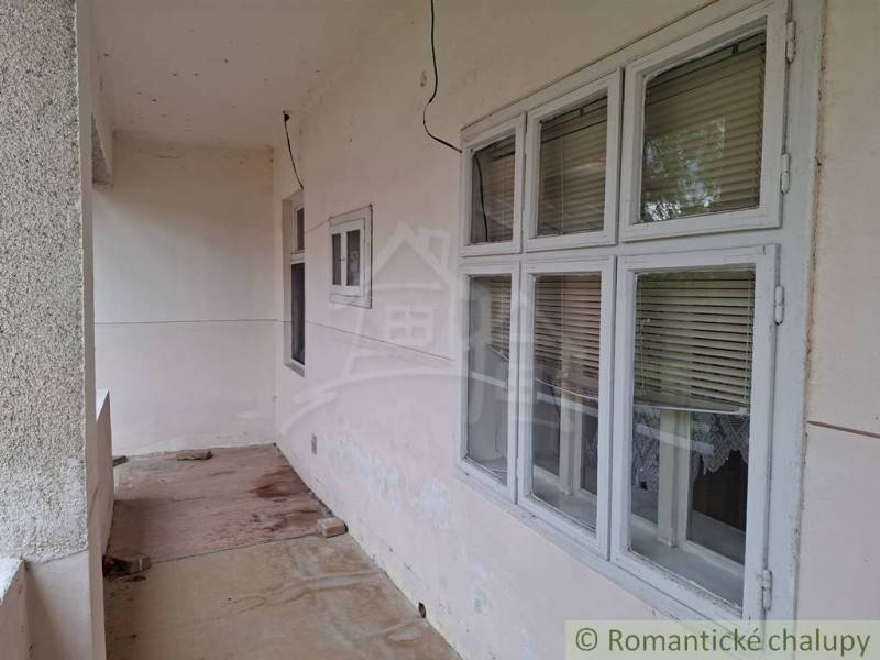 Rodinný dům v Mužli s průchozí terasou, okny se žaluziemi a betonovou podlahou.