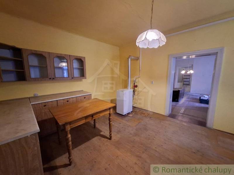Kuchyně v rodinném domě s nábytkem a svítidlem, podlaha s dřevěným dekorem.