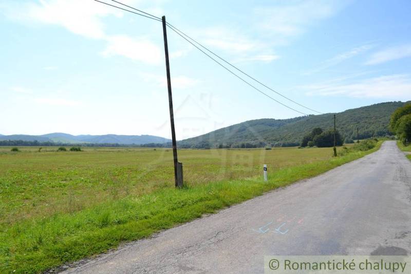 Rozsáhlé zemědělské a lesní pozemky u města Šandal s výhledem na kopcovitou krajinu.
