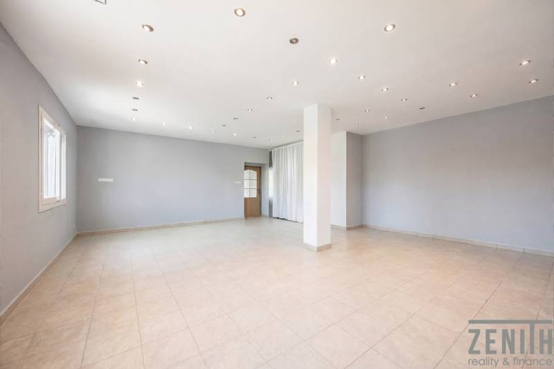 Obchodní prostory s bílými stěnami, keramickou podlahou a bodovým osvětlením.