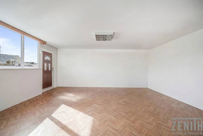 Prostorné obchodní prostory s velkým oknem a podlahou s dřevěným dekorem.