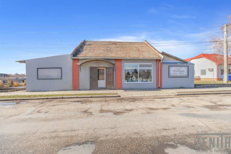 Obchodní prostory ve městě Okoč s výkladními okny a šikmou střechou.