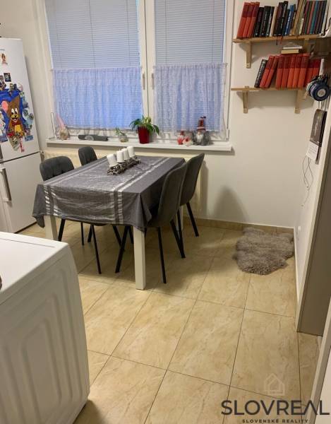 Jídelní kout v 2-pokojovém bytě s bílým stolem a šedými židlemi.
