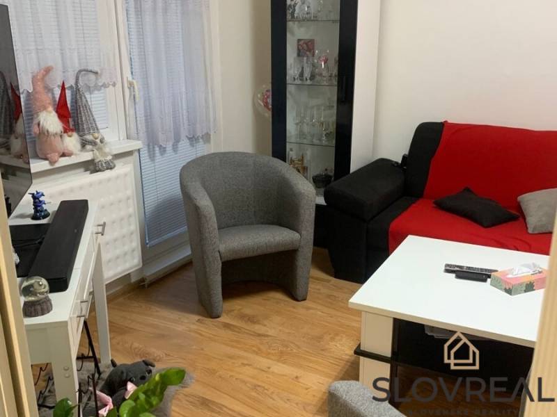 Obývací pokoj v 2pokojovém bytě s barevným nábytkem a podlahou s dřevěným dekorem.