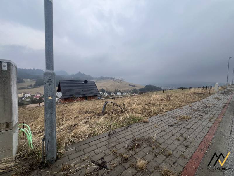 Pohled na pozemky - bydlení ve Staré Ľubovni s viditelným chodníkem a domem.
