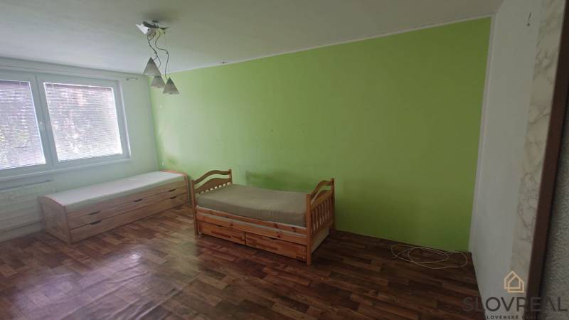 Interiér 2-pokojového bytu s dvěma postelemi, podlaha s dřevěným dekorem, zelená stěna.