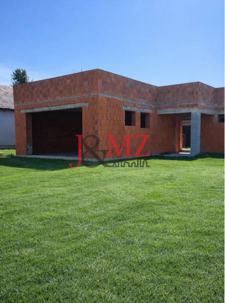 Nedokončený rodinný dům v Dolní Seči s travnatým pozemkem a základy z cihel.