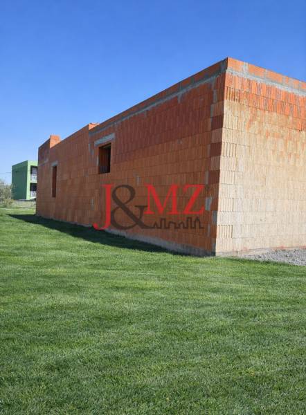 Nedokončená stavba rodinného domu v Dolní Seči obklopená upraveným trávníkem.