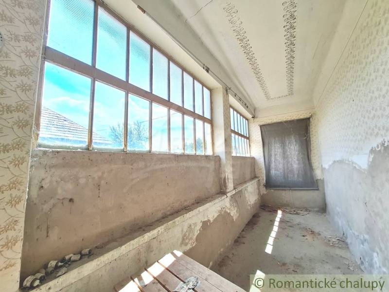 Chata v Kamenném Mostě s dlouhou verandou a velkými okny, potřebuje renovaci.