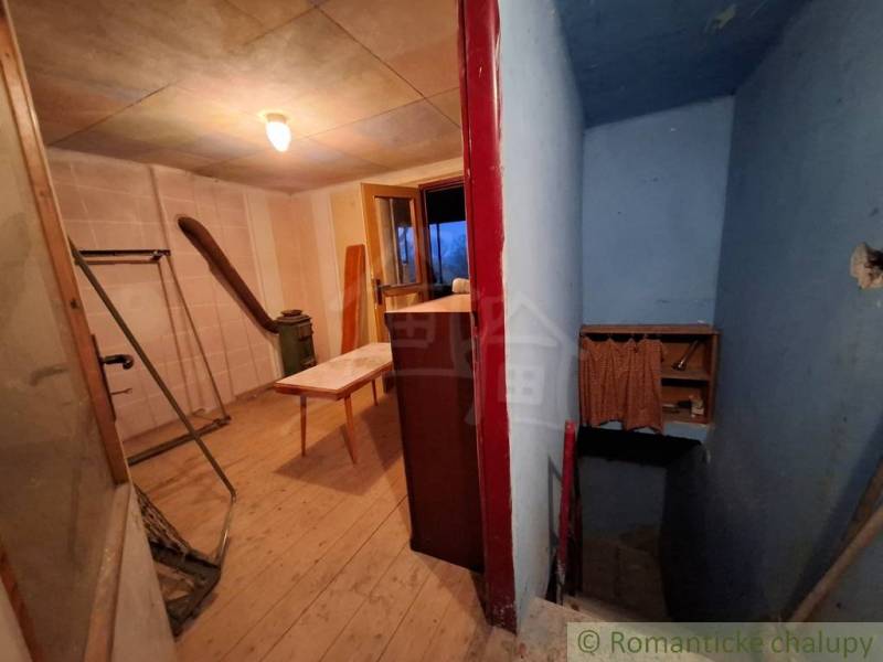 Interiér chaty s podlahou s dřevěným dekorem, chodbou a stolem.