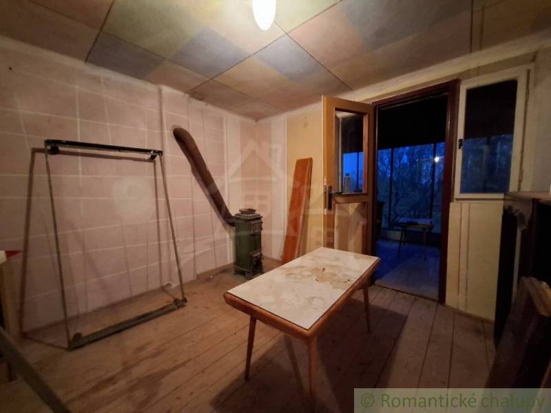 Interiér chaty s podlahou s dřevěným dekorem a starým nábytkem.