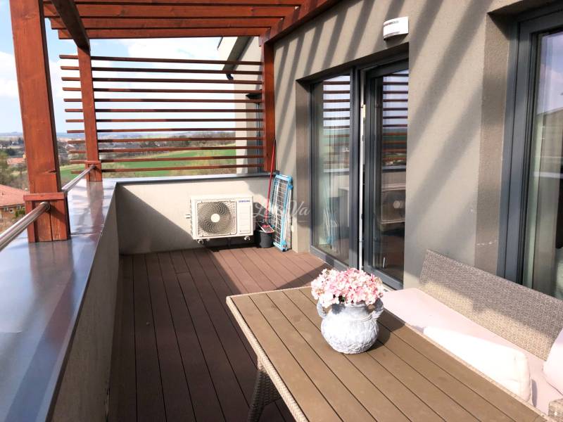 Terasa 2-pokojového bytu s výhledem na okolí a květinovou dekorací.