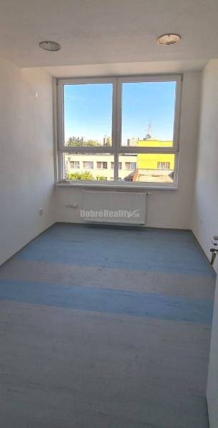 Světlá kancelář s velkým oknem, podlaha s dřevěným dekorem, výhled na město.