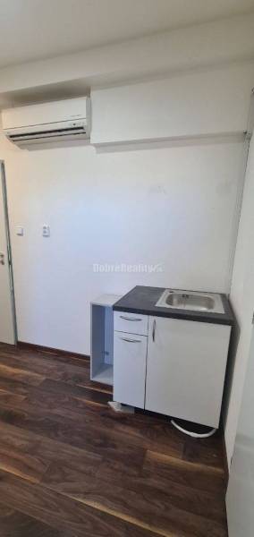 Kancelář s klimatizací, umyvadlem a podlahou s dřevěným dekorem.