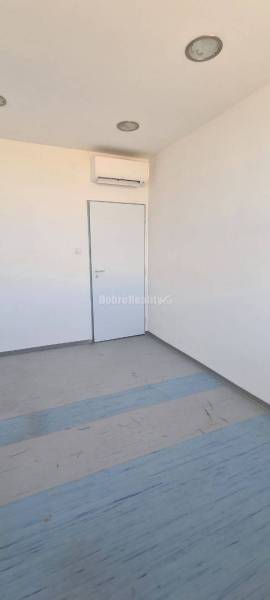 Kancelář s bílými stěnami a klimatizací, podlahou s dřevěným dekorem.