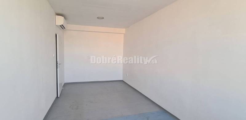 Světlé kancelářské prostory s bílými stěnami a oknem, podlaha s dřevěným dekorem.