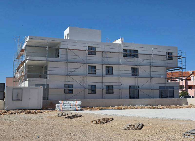 Budova ve městě SRIMA s lešením a nepořádkem na zemi.