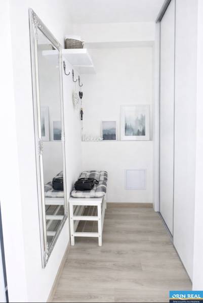 Vstupní hala v 2-pokojovém bytě se zrcadlem, lavičkou a podlahou s dřevěným dekorem.