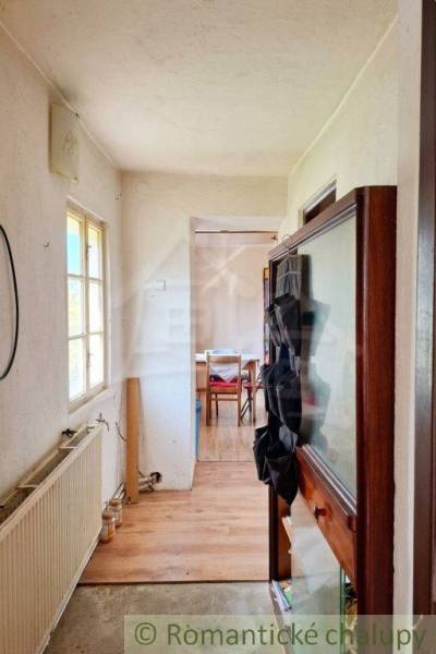 Interiér rodinného domu s úzkou chodbou a místností na konci.
