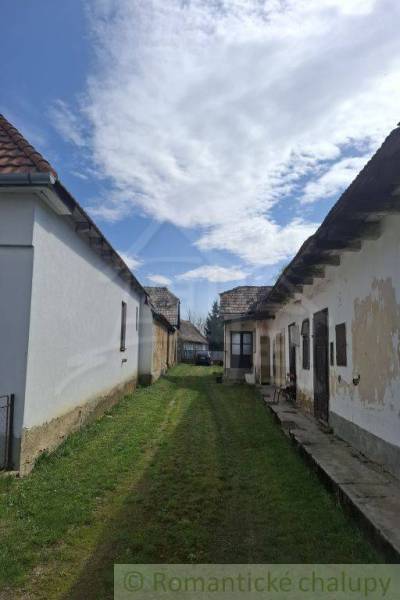 Starší rodinný dům se zahradou a oblačnou oblohou.